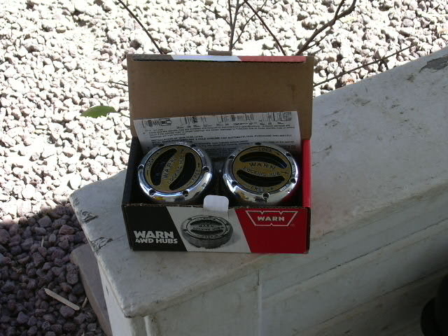 Pair of chrome Warn 4WD locking hubs in their open retail box on concrete