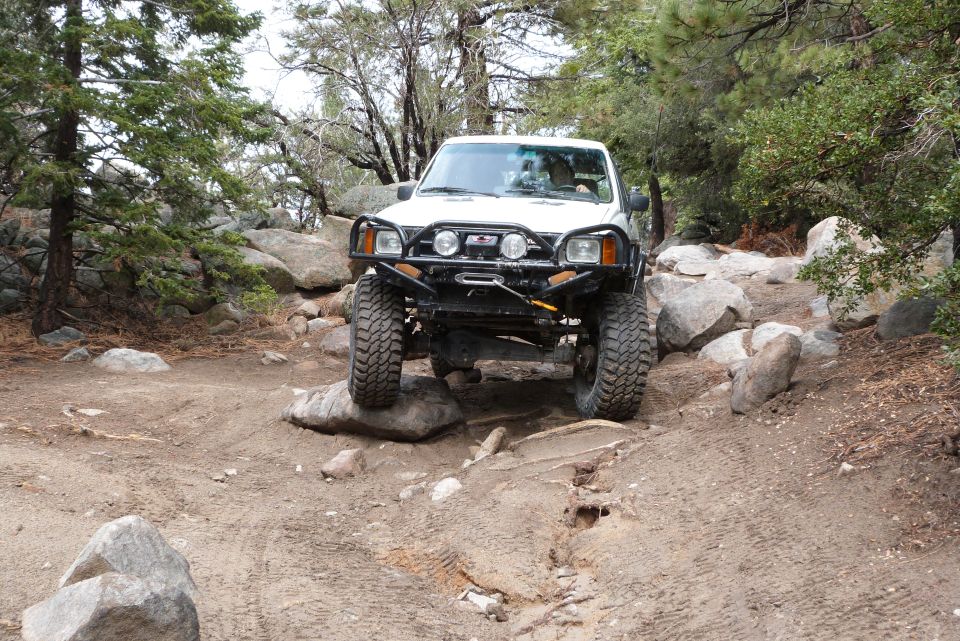 White SUV with off-road modifications navigating a rocky trail