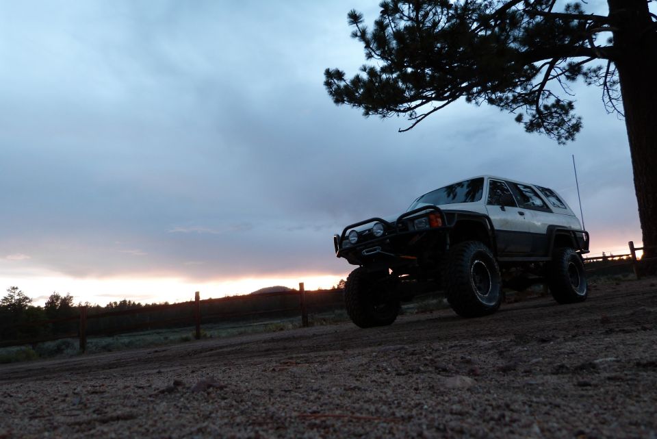 Modified 1985 Toyota 4Runner with off-road tires and bumper parked on dirt hill at dusk