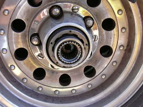 1991 Ford Bronco - Close-up of a polished aluminum beadlock-style wheel with the center cap removed, showing the exposed front hub, five lug nuts and the spli…