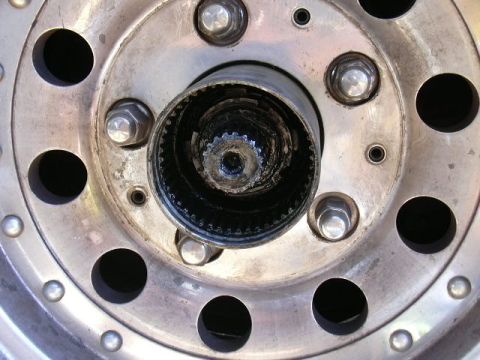 1991 Ford Bronco - Extreme close-up of a wheel center with the locking hub cap removed, showing the greasy splined axle shaft stub, the toothed hub gear ring…