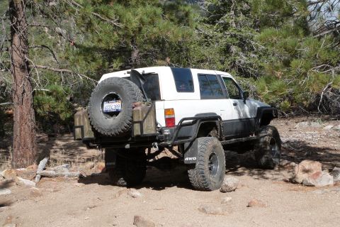 1985 Toyota 4Runner - Modified Toyota 4Runner with off-road tires and external fuel containers sits on a rocky, wooded trail.