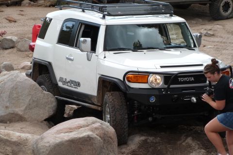 1985 Toyota 4Runner - Toyota FJ Cruiser tackles rocky terrain, with a photographer capturing the moment.