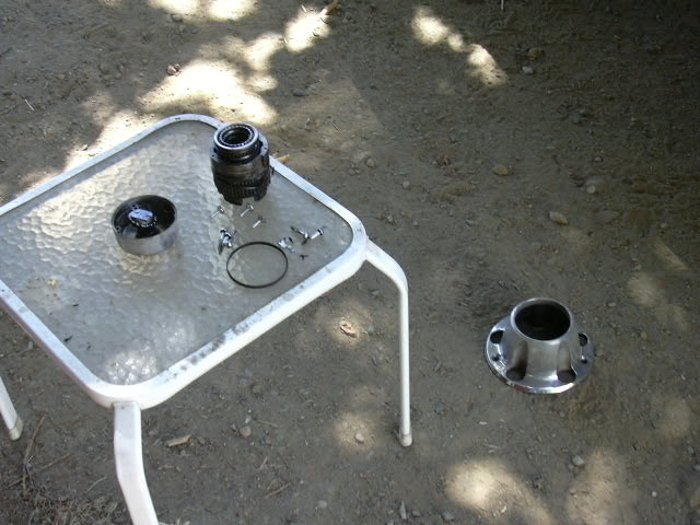 Bronco front-axle parts on a glass patio table, chrome hub on the ground beside it