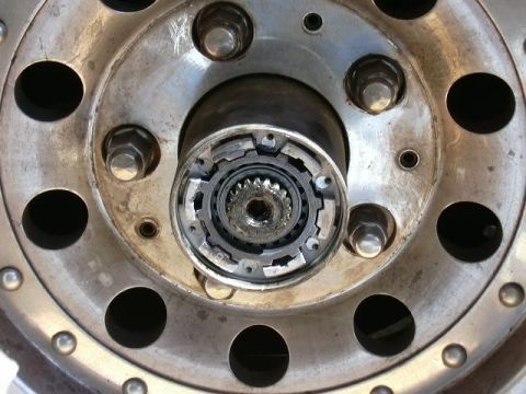 1991 Ford Bronco - Close-up of a five-lug aluminum wheel with the locking-hub cap removed, exposing the splined axle shaft end, internal hub clutch ring and s…