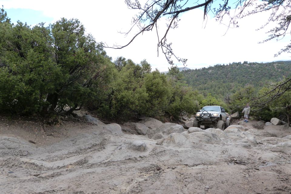 Silver Toyota pickup truck with large tires navigating a rocky, off-road trail