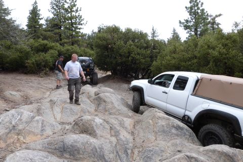 1985 Toyota 4Runner - A white Toyota Tacoma pickup truck with a tan soft top is seen on a rocky off-road trail, with another vehicle and two people in the backgr…