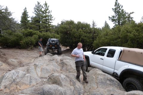 1985 Toyota 4Runner - Off-road vehicles tackle a challenging rocky path in a wooded area.