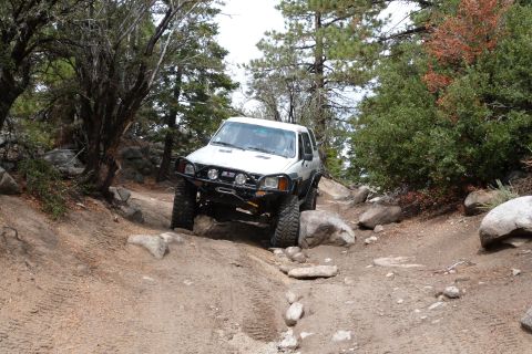1985 Toyota 4Runner - Toyota 4Runner tackling a challenging off-road course with large rocks and trees.