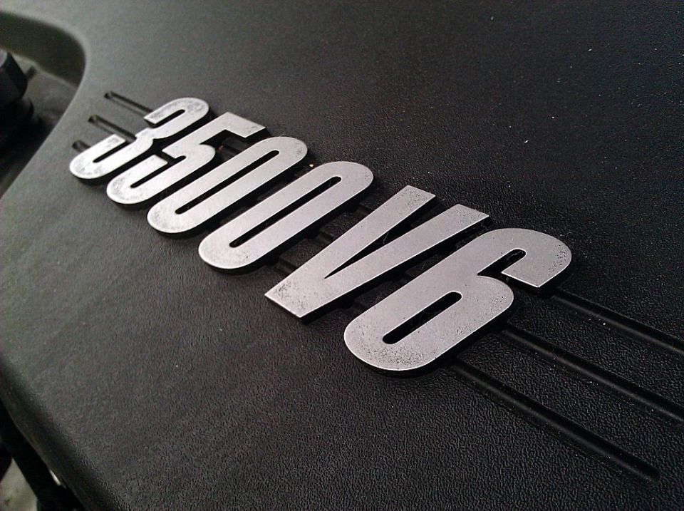 Close-up of a '350 V6' badge on a black engine cover