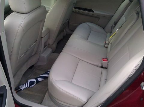 2008 Chevrolet Impala - The interior of a car, light-colored leather seats and an umbrella on the floor mat.