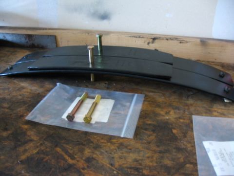 1995 Ford Bronco - New leaf spring and hardware laid out on a workbench.