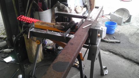 1989 Ford Bronco - A metal beam is positioned on saw horses, ready for cutting, with various tools and supplies in the background.