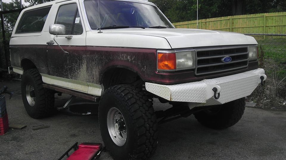 White and maroon 1989 Ford Bronco with custom diamond plate bumper and large tires