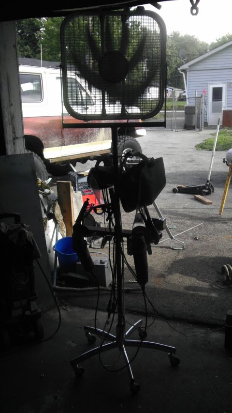 1989 Ford Bronco - A white and red van is visible behind a large fan and welding equipment in a garage.