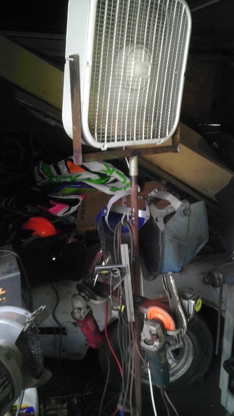 1989 Ford Bronco - A collection of tools and a shop fan are set up in front of a car in a garage.