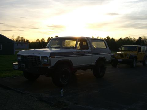 1979 Ford Bronco - A two-tone Ford Bronco and a yellow Jeep are parked outdoors as the sun sets.