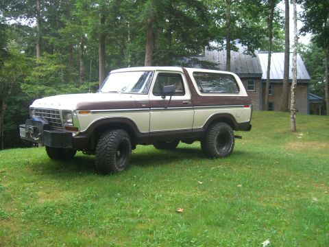 1979 Ford Bronco - This two-tone Ford Bronco is parked on a grassy lawn with a house in the background.