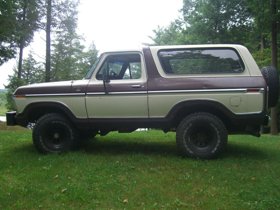 Two-tone brown and beige Ford Bronco with a spare tire mounted on the rear, seen from the side