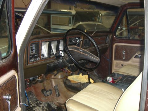 1979 Ford Bronco - The interior of this 1979 Ford Bronco features woodgrain trim, a tan interior, and a prominent steering wheel.
