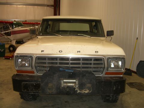 1979 Ford Bronco - A white 1979 Ford Bronco is parked inside a garage, facing the camera with a winch on its front bumper.