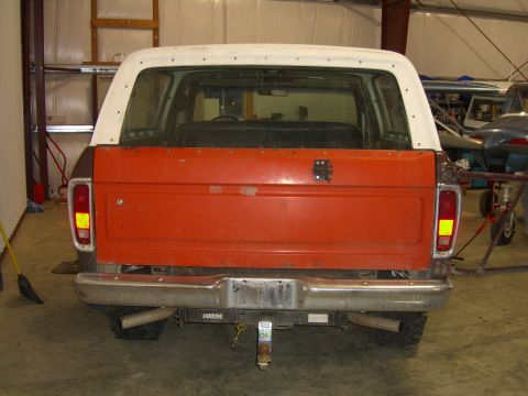 1979 Ford Bronco - Rear view of a 1978 Ford Bronco, showing its orange tailgate, white top, and chrome bumper.