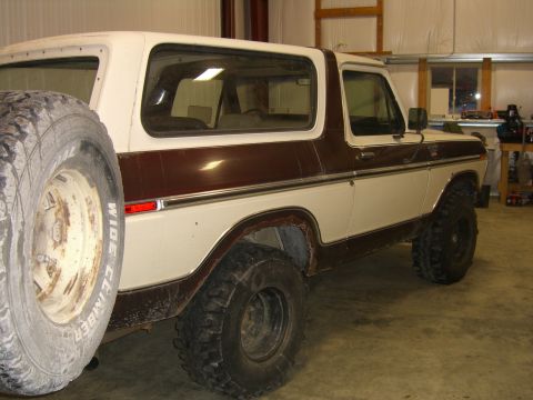 1979 Ford Bronco - This two-tone Ford Bronco is parked indoors, showing its side profile and spare tire.