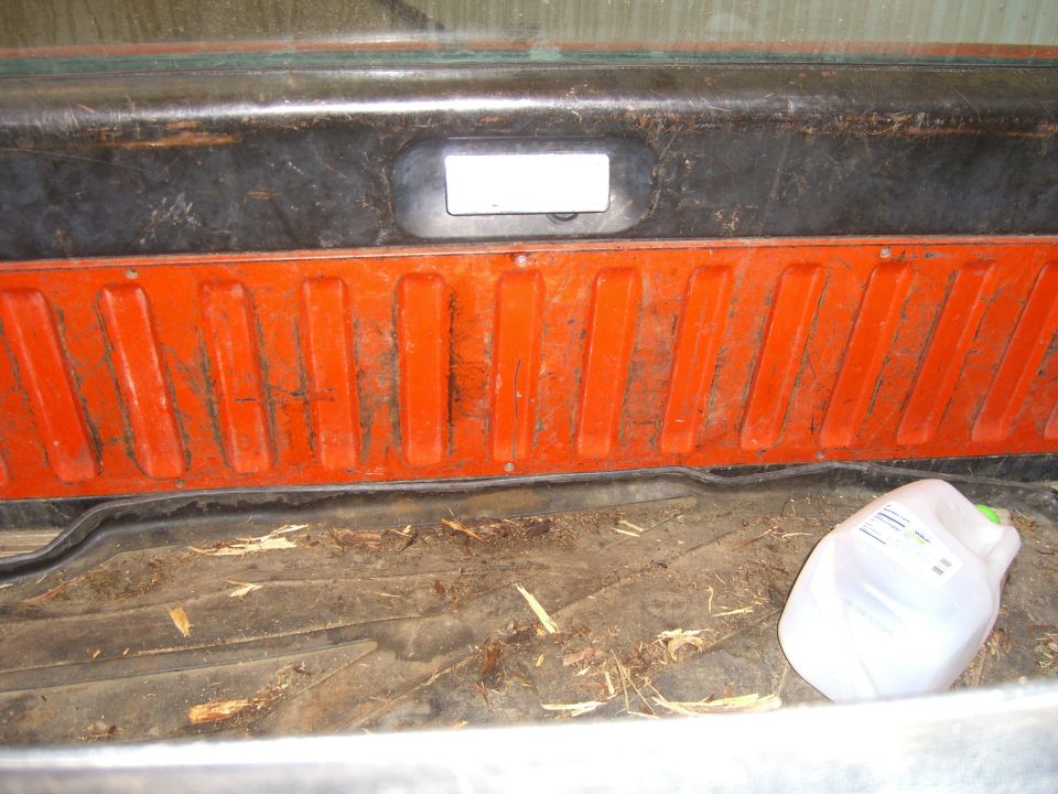 Interior cargo area of a vehicle showing a plastic jug and debris on the floor