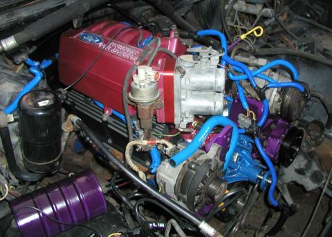 1988 Ford Bronco - A close-up view of a modified engine bay, custom-colored components and extensive blue tubing.