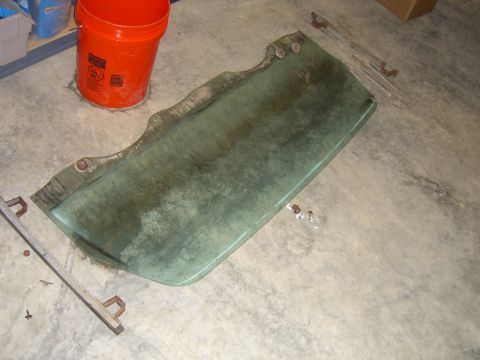 1979 Ford Bronco - A green car door lies on a concrete floor, with an orange bucket nearby.