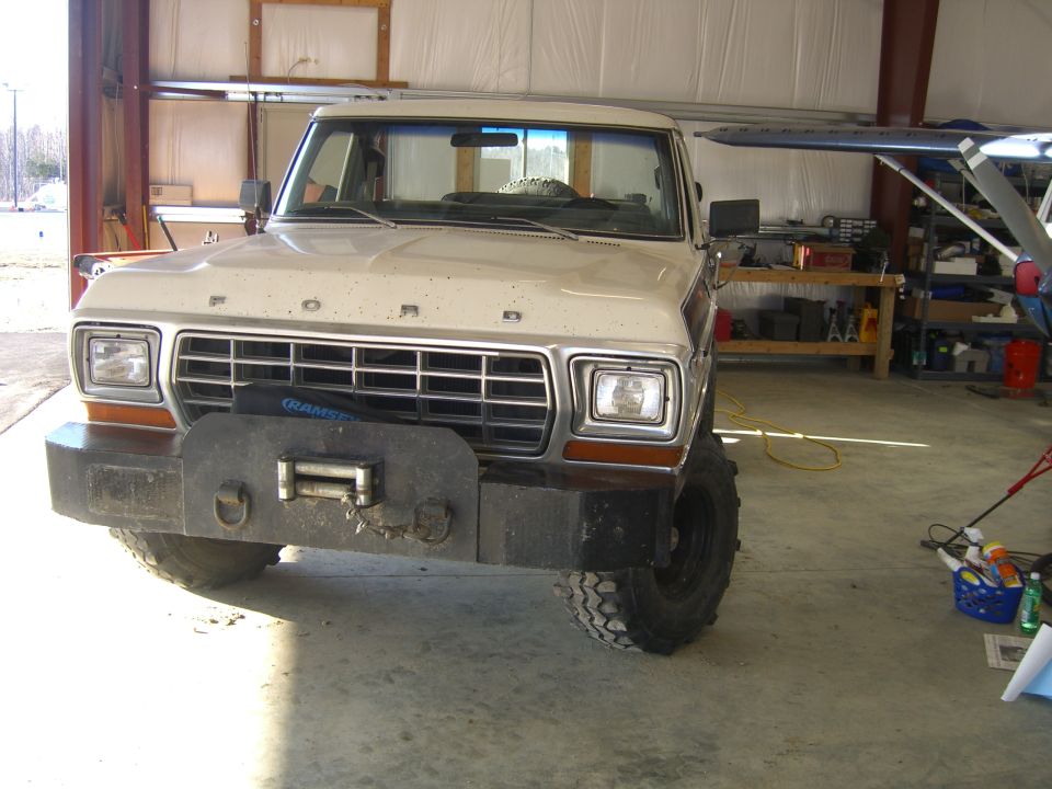 Ford Bronco with custom bumper and winch, parked inside a garage next to a small airplane