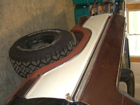 1979 Ford Bronco - A spare tire rests beside the fender of a vehicle, showing off its chrome trim and two-tone paint.