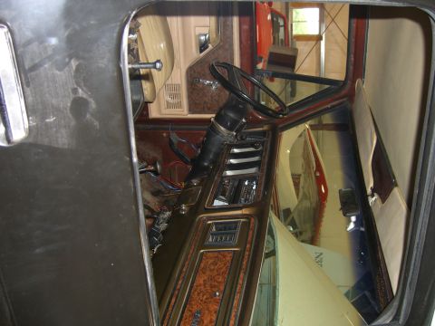 1979 Ford Bronco - The interior of a 1979 Ford Bronco shows woodgrain trim on the dashboard and door panels, with some wiring exposed.