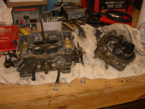 1979 Ford Bronco - Carburetors disassembled on a workbench, with various tools and a battery charger visible in the background.