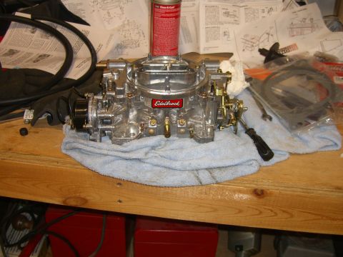 1979 Ford Bronco - A shiny Edelbrock carburetor sits on a blue towel, surrounded by repair diagrams and tools.