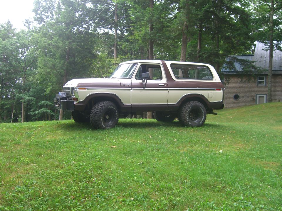 Two-tone brown and cream 1978 Ford Bronco with off-road tires parked on a grassy hill