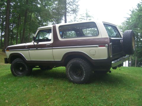 1979 Ford Bronco - This two-tone Ford Bronco is shown from the rear three-quarter angle, parked outdoors on a grassy lawn.