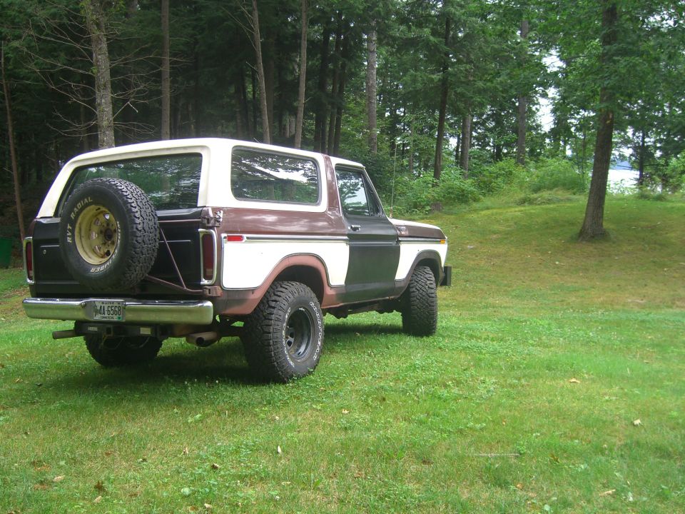 Two-tone brown and white 1978 Ford Bronco with a spare tire mounted on the rear, parked on a grassy lawn