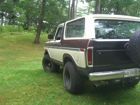 1979 Ford Bronco - This 1979 Ford Bronco features a distinctive two-tone brown and white paint scheme and is parked outdoors on a grassy lawn.