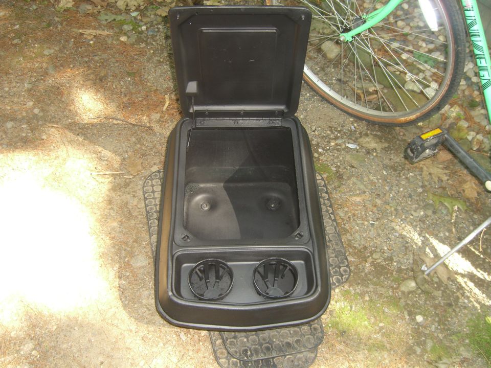 Black center console with two cup holders and open storage compartment