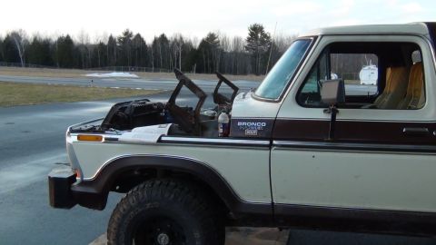 1979 Ford Bronco - A two-tone white and brown 1978 Ford Bronco is shown with its hood open, revealing engine parts.