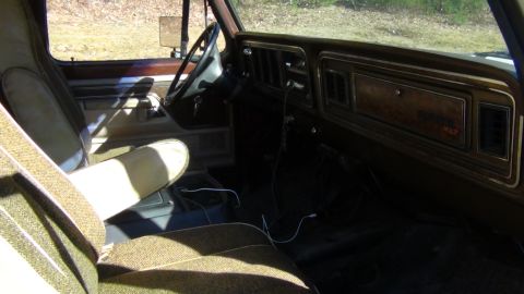 1979 Ford Bronco - The interior of a 1979 Ford Bronco features patterned cloth seats and a wood-grain accented dashboard.