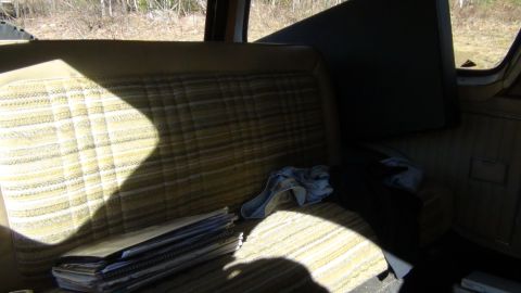 1979 Ford Bronco - Interior view of a vehicle's bench seat, with papers and a cloth on the seat.
