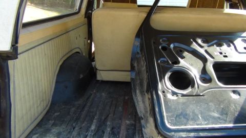 1979 Ford Bronco - The interior of a 1979 Ford Bronco is visible, with tan seats and a bare door frame.