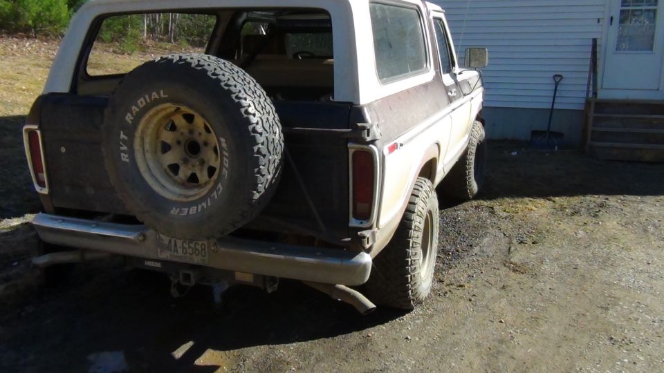 Rear view of a white and brown Ford Bronco with a spare tire mounted on the back. License plate reads AX 6568