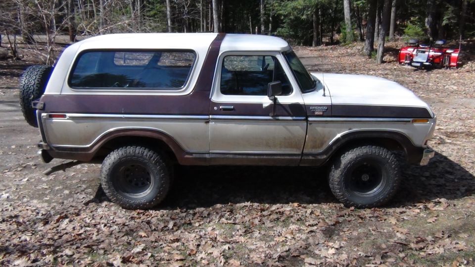 Side view of a two-tone brown and white Ford Bronco with a spare tire on the back
