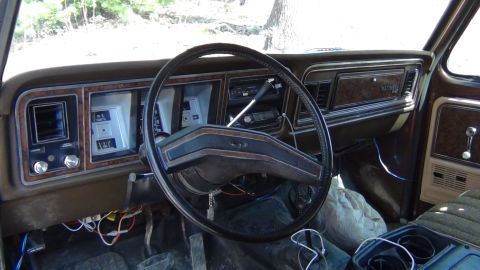 1979 Ford Bronco - The interior of a 1979 Ford Bronco shows its dashboard with wood grain accents and a large steering wheel.