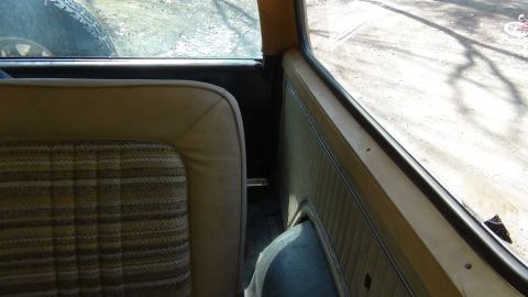1979 Ford Bronco - Interior view of a 1979 Ford Bronco, highlighting the plaid seat fabric and wood-grain door panel.