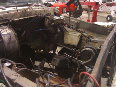 1979 Ford Bronco - The engine bay of a vehicle is shown disassembled, with other vehicles and an airplane in the background.