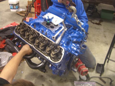 1979 Ford Bronco - Engine assembly in progress, with a chain hoist lifting the blue V8 motor.